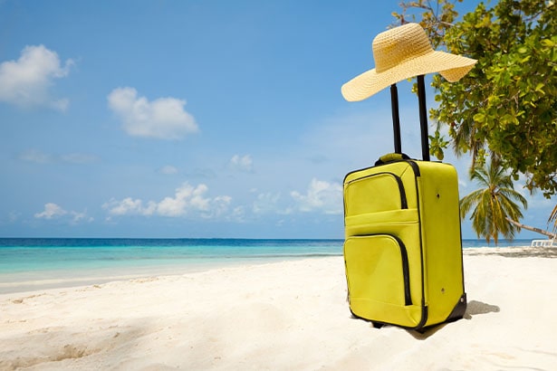 Valigia e cappello sulla spiaggia